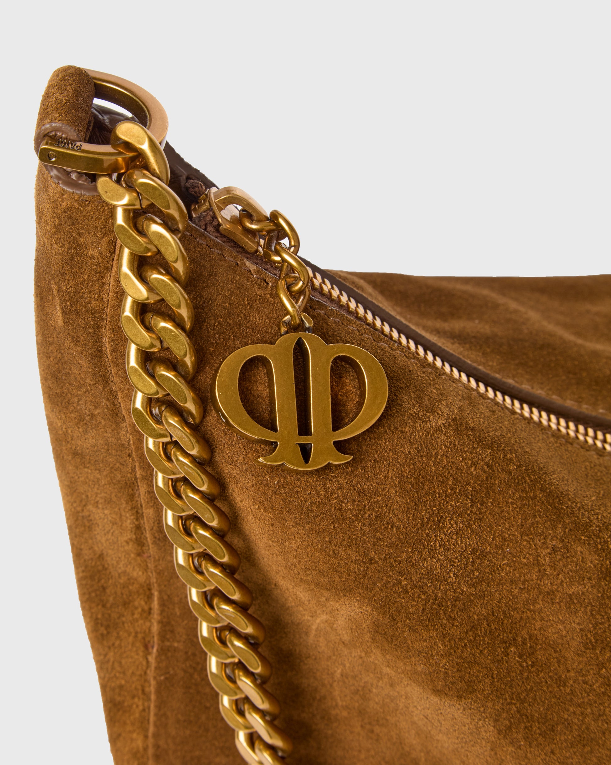 Close-up of a brown suede shoulder bag with a gold-tone chain strap and a double-P monogram charm, set against a light gray background.