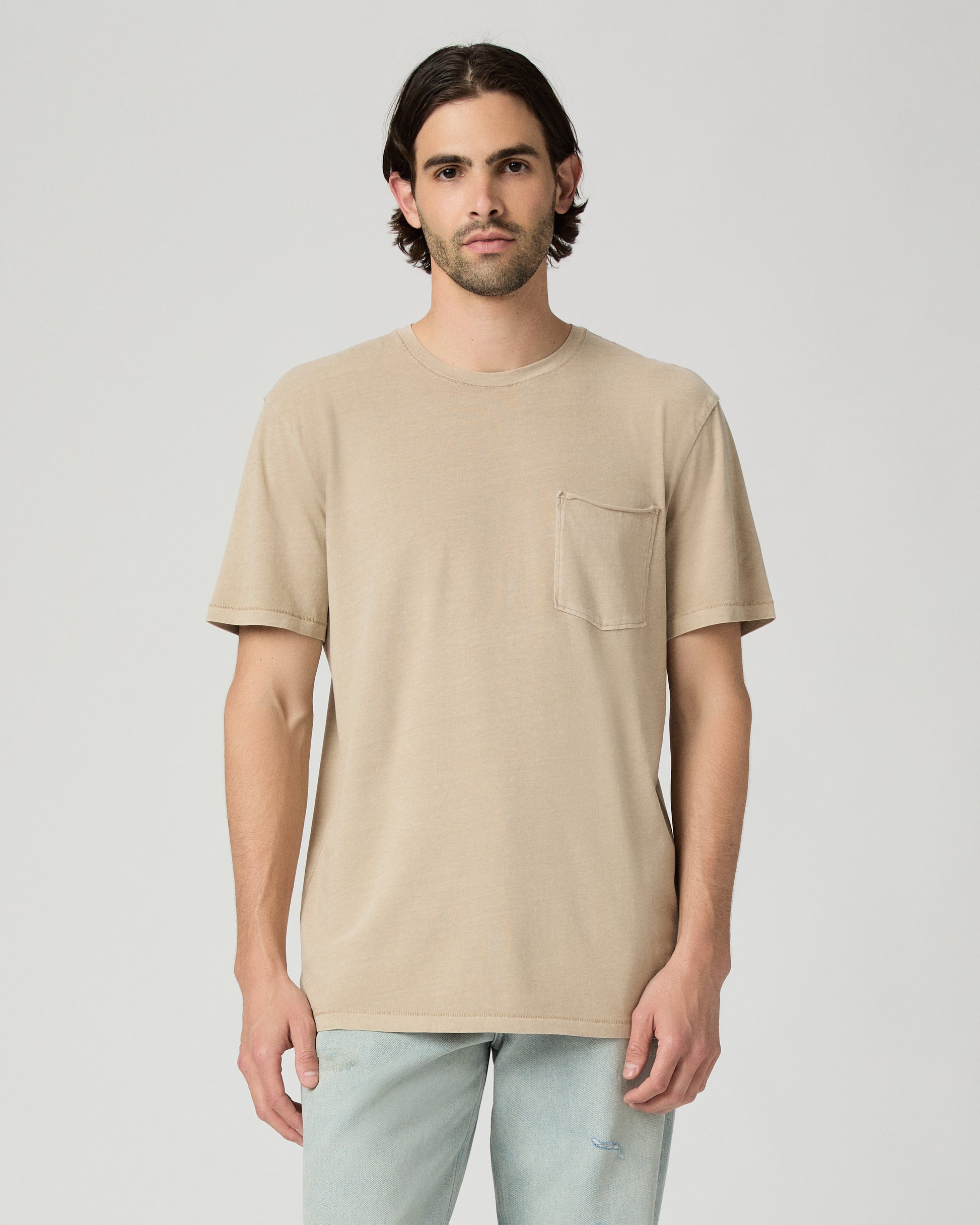 Men wearing a tan color tee with light blue jeans