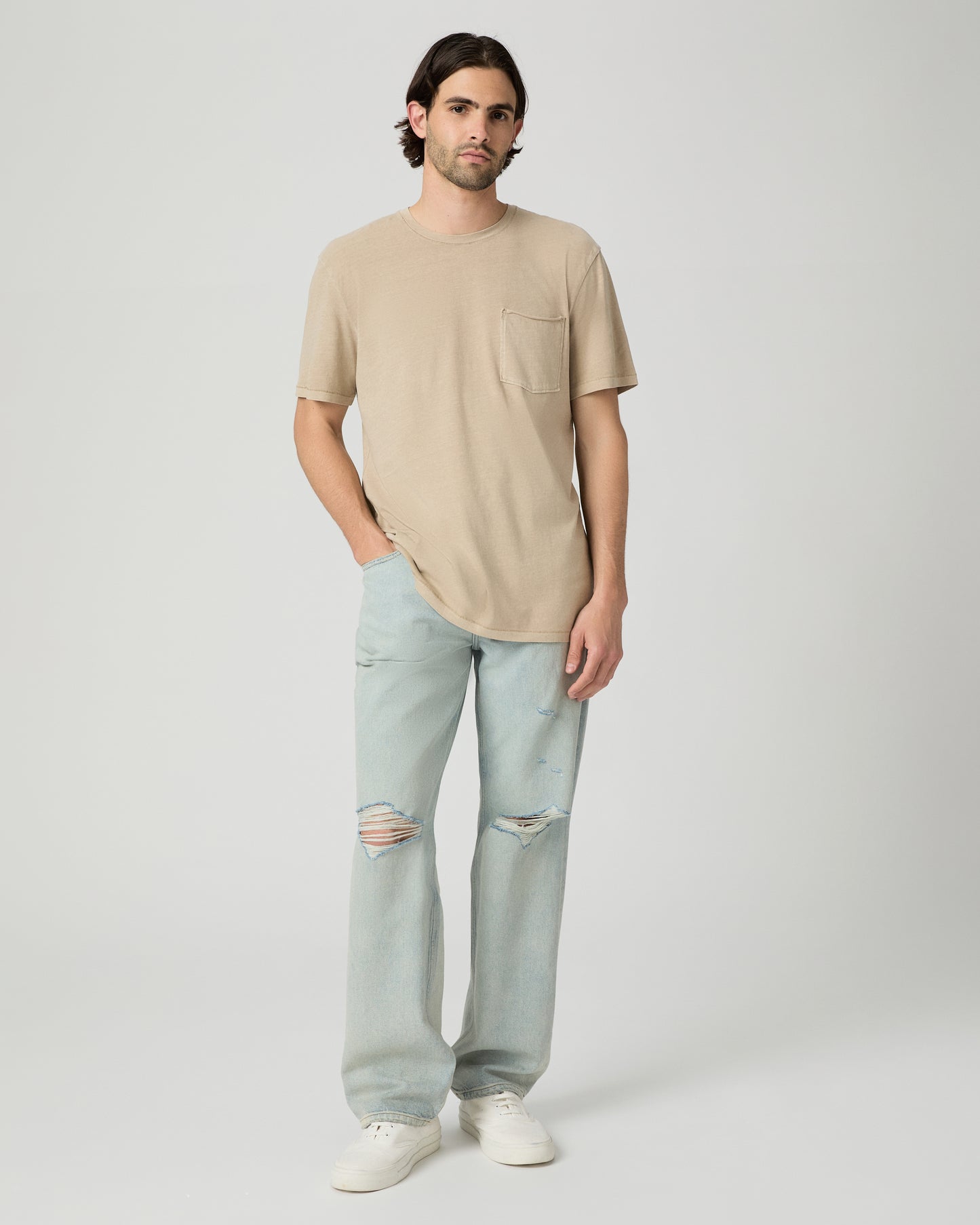 Men wearing a tan color tee with light blue jeans