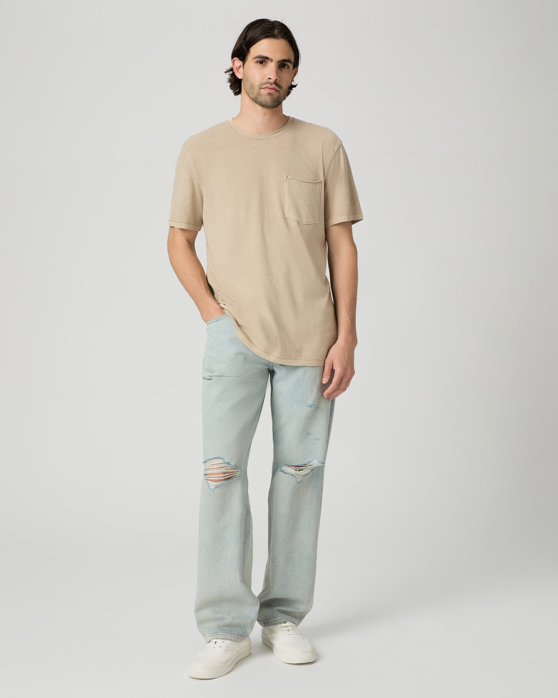 Men wearing a tan color tee with light blue jeans