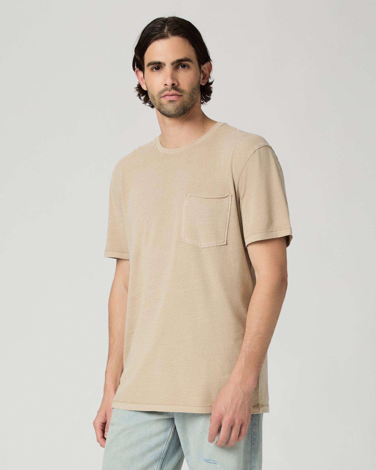 Men wearing a tan color tee with light blue jeans
