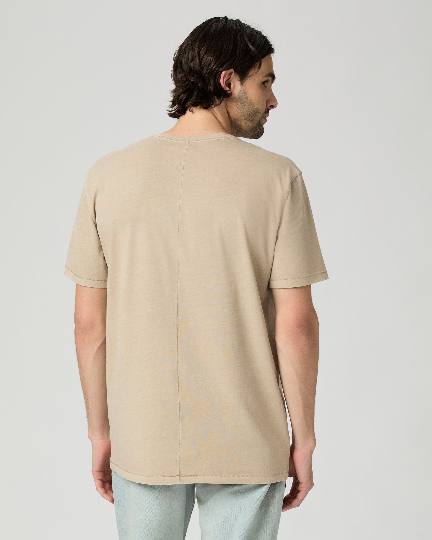 Men wearing a tan color tee with light blue jeans