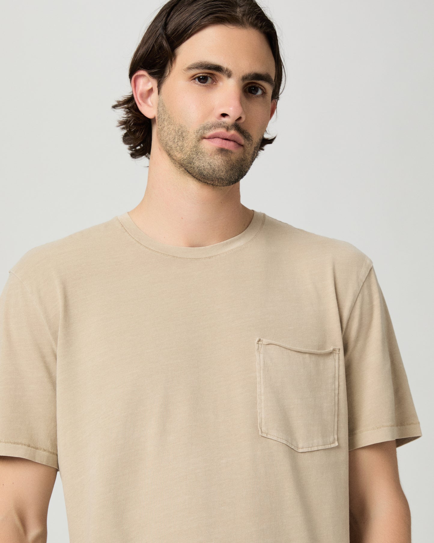 Men wearing a tan color tee with light blue jeans
