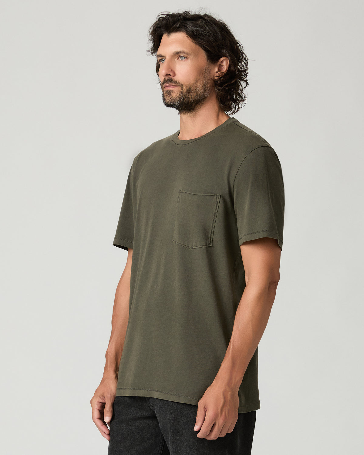 Three-quarter side view of a man wearing the vintage fatigue green Ramirez Tee, showing the raw-edge chest pocket and relaxed short-sleeve fit.