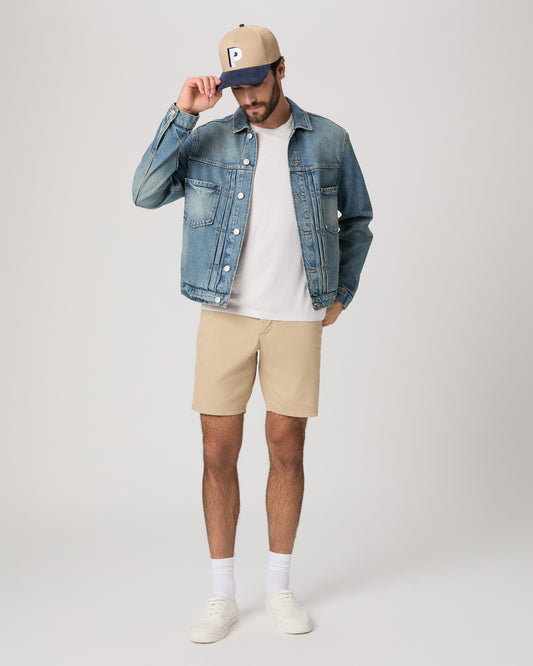 Men wearing a denim jacket, white tee, beige color shorts paired with a baseball cap and white sneakers