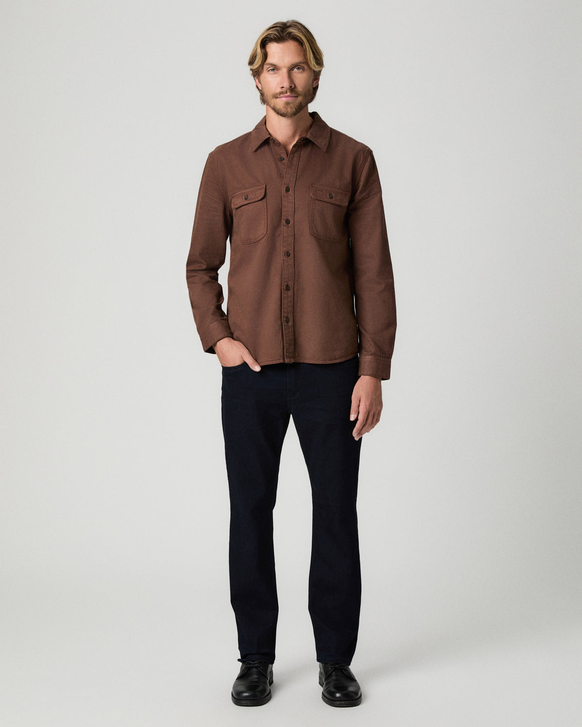 Full-length view of model with one hand in his pocket, wearing the Martin Shirt in Vintage Sepia Clay with dark jeans and black boots