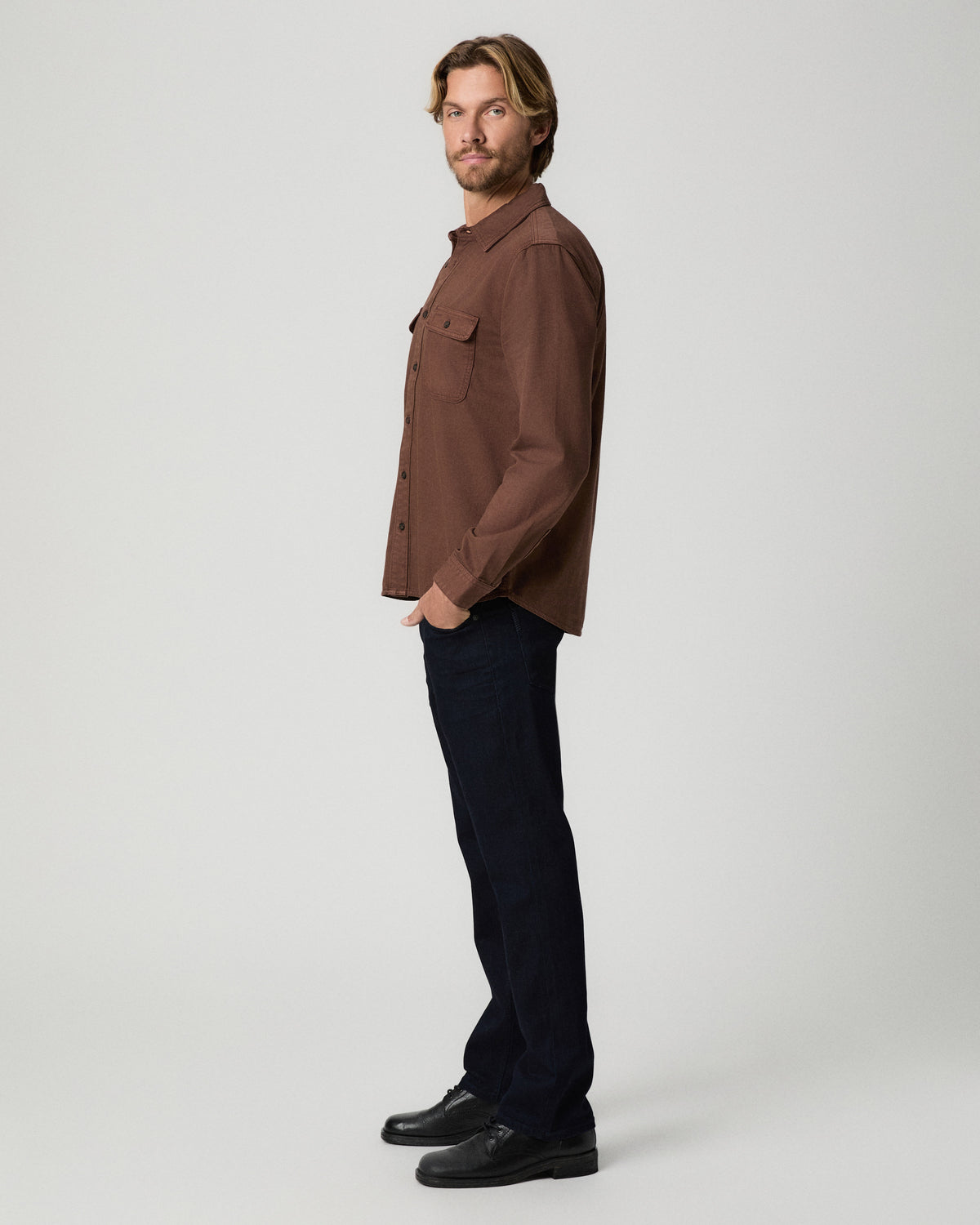 Side profile of model with one hand in his pocket, wearing the Martin Shirt in Vintage Sepia Clay with dark jeans and black boots