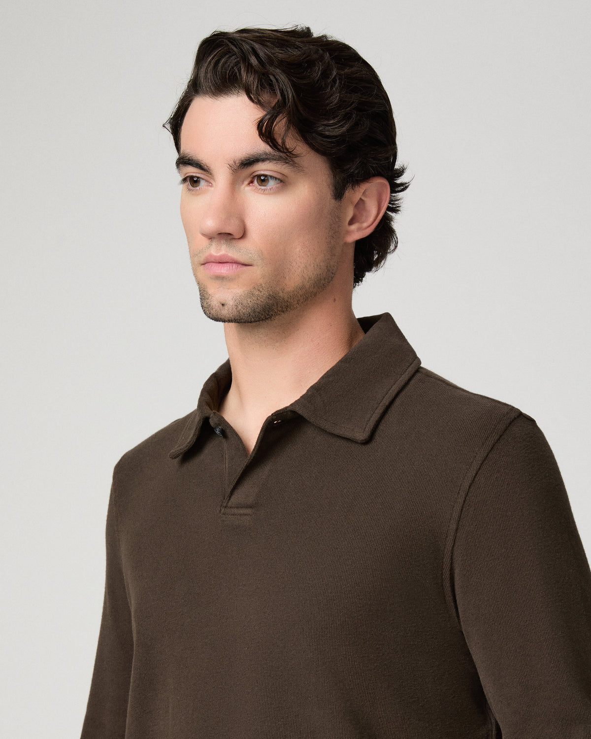 Man wearing a brown shirt and brown pants against a white background