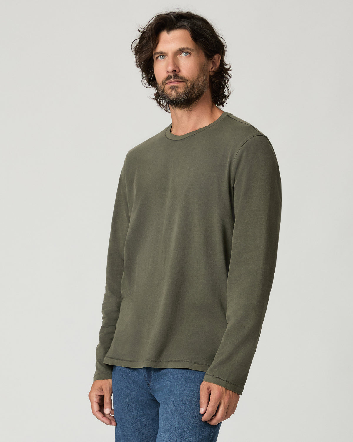 Three-quarter side view of a man wearing the vintage fatigue green Enzo Shirt, highlighting the raw-edge cuff and relaxed long-sleeve silhouette.