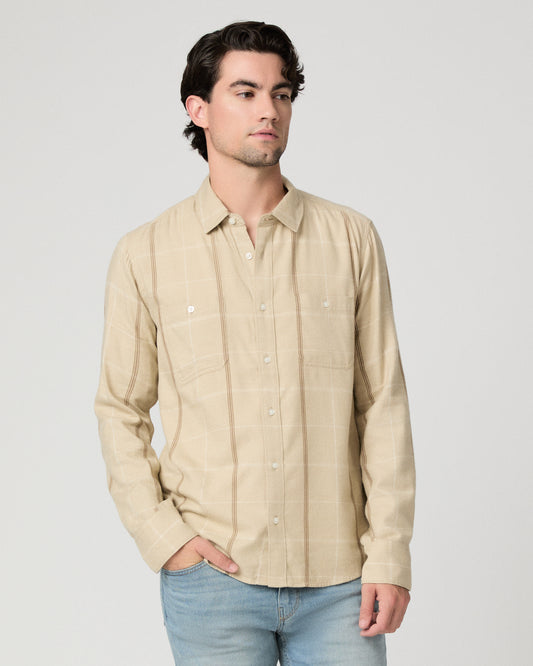 Man wearing beige shirt with light blue jeans against a white background