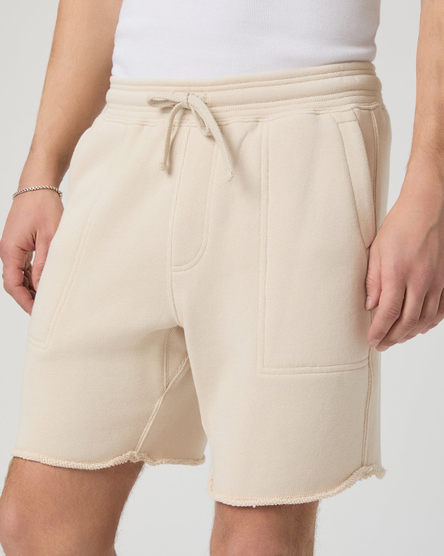 Man wearing a white shirt, beige shorts on a plain background