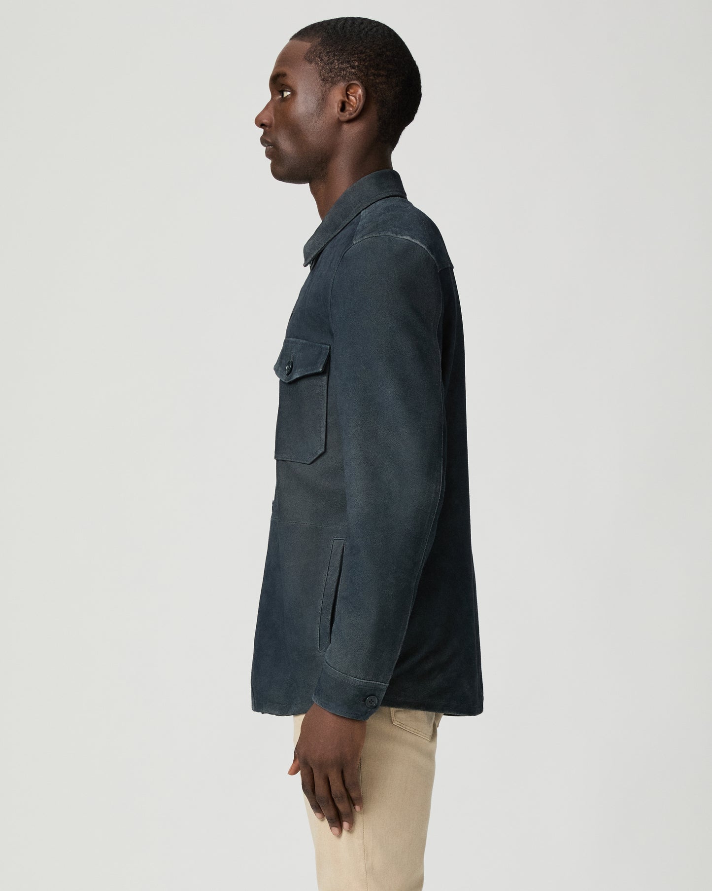 Man wearing a dark blue jacket with button details on a light gray background