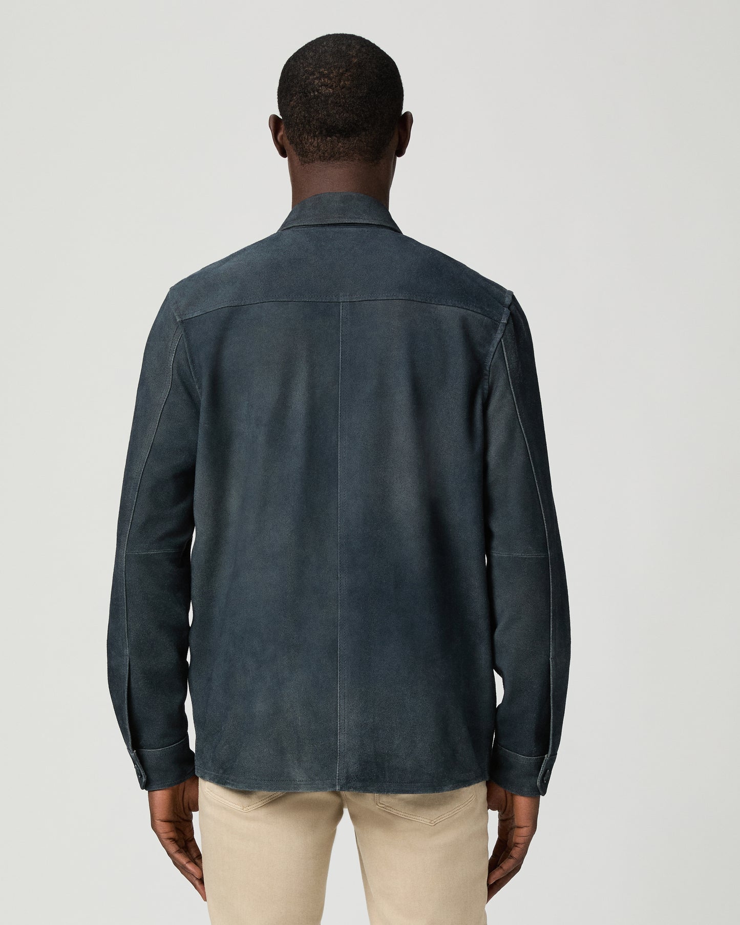 Man wearing a dark blue jacket with button details on a light gray background