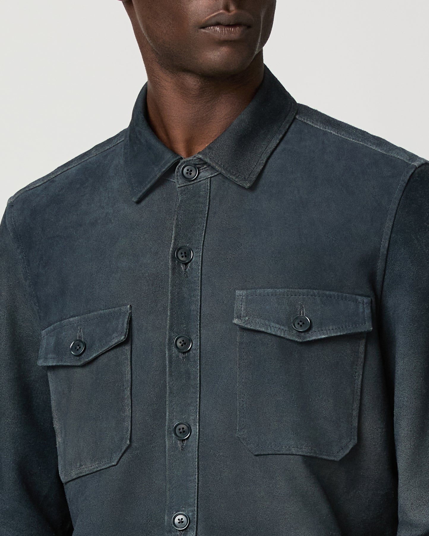 Man wearing a dark blue jacket with button details on a light gray background