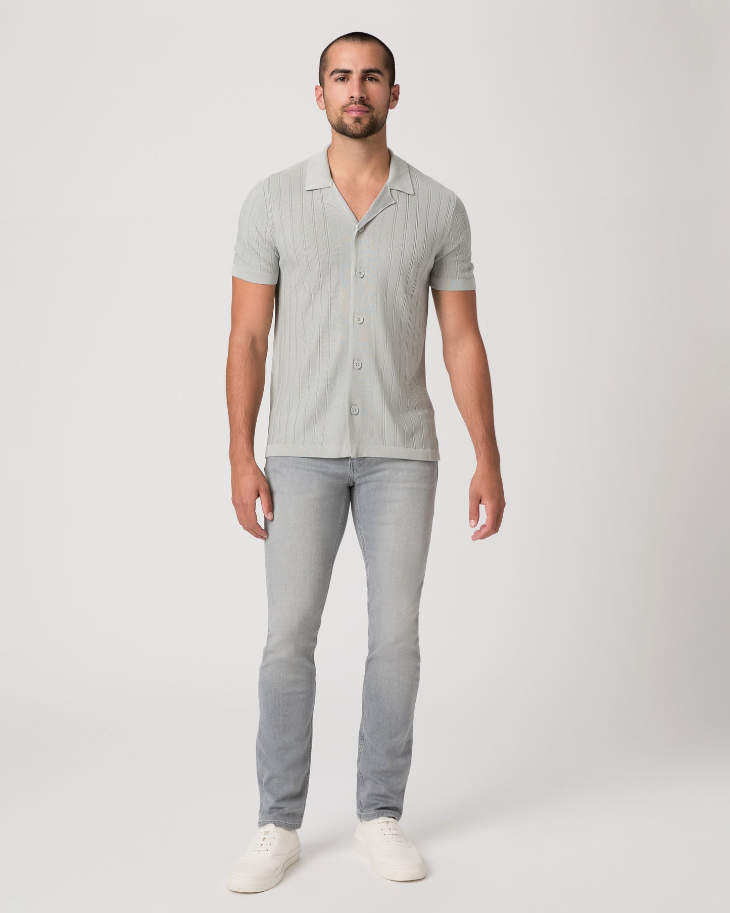 Man wearing a light gray short-sleeve shirt with a collar and gray pants on a white background