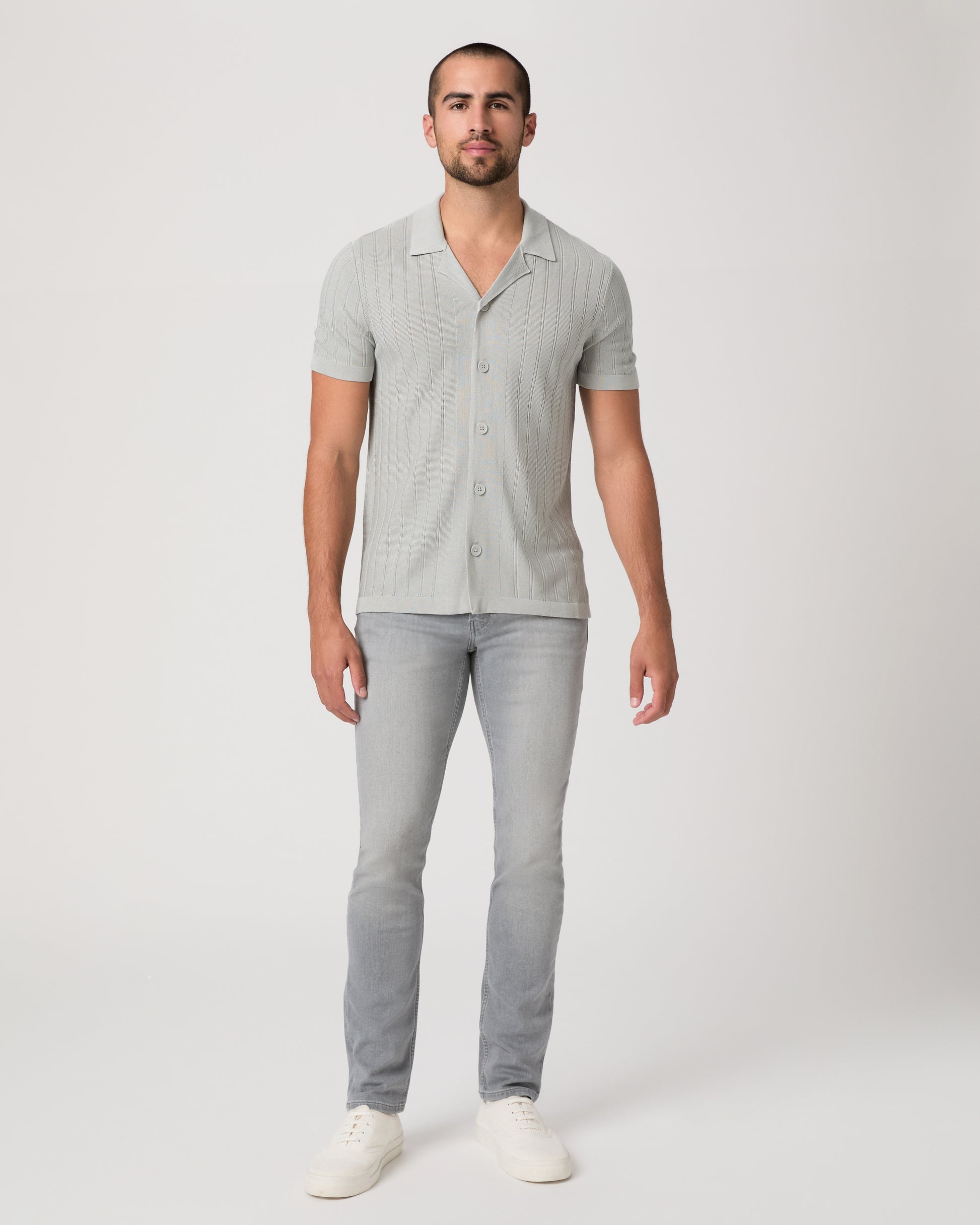 Man wearing a light gray short-sleeve shirt with a collar and gray pants on a white background