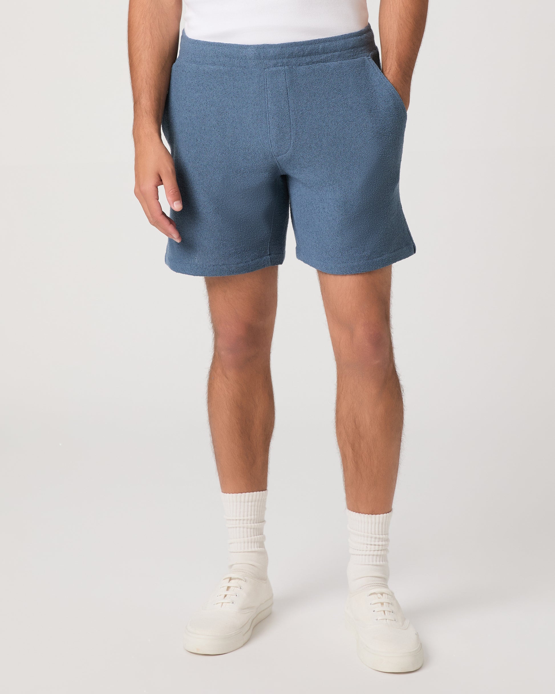 Man wearing a white and shorts set with white shoes on a light gray background