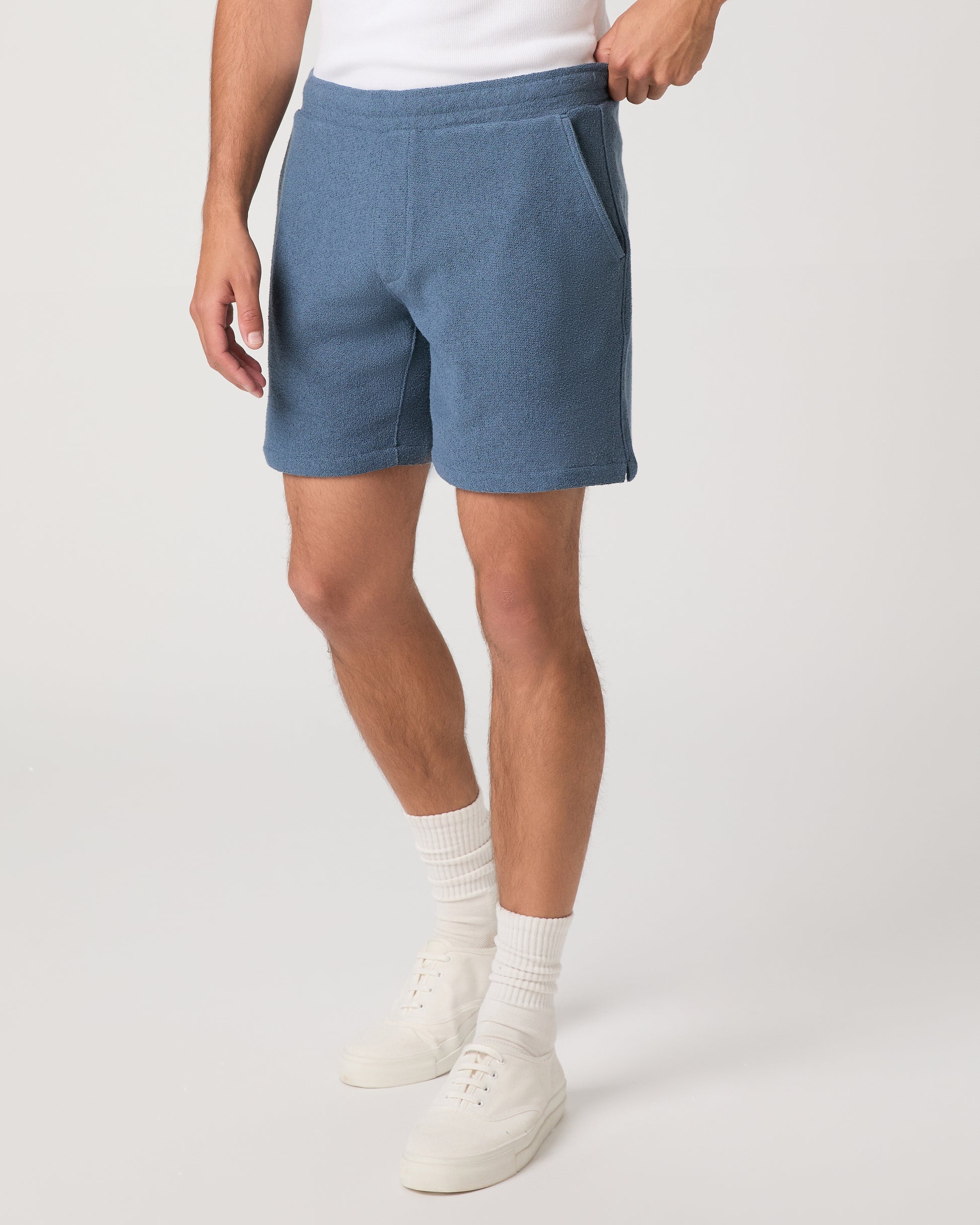Man wearing a white and shorts set with white shoes on a light gray background