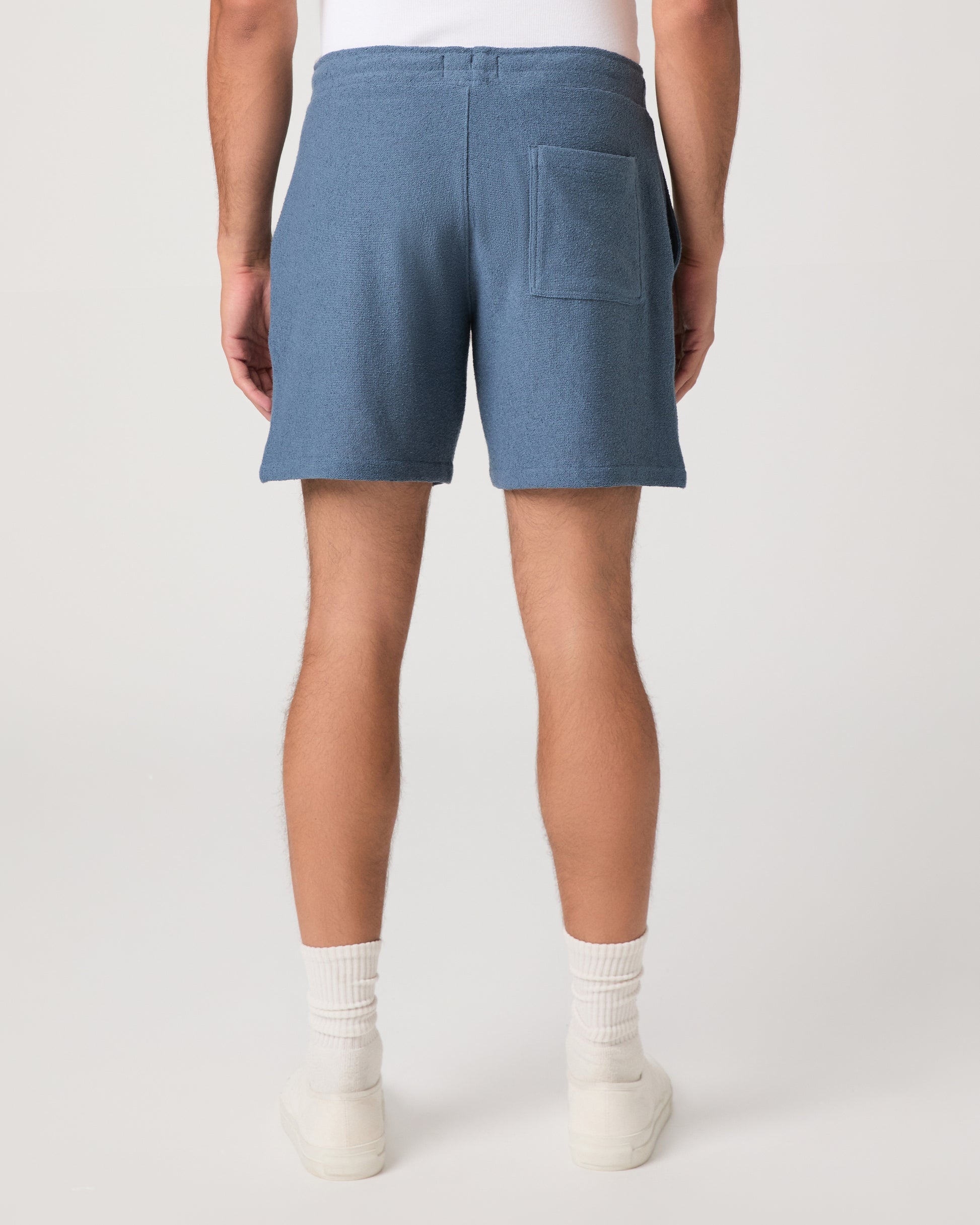 Man wearing a white and shorts set with white shoes on a light gray background
