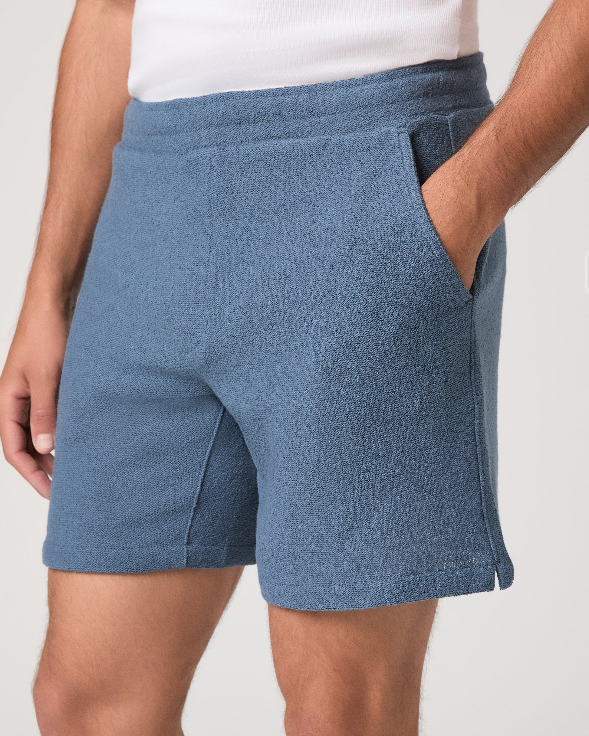 Man wearing a white and shorts set with white shoes on a light gray background
