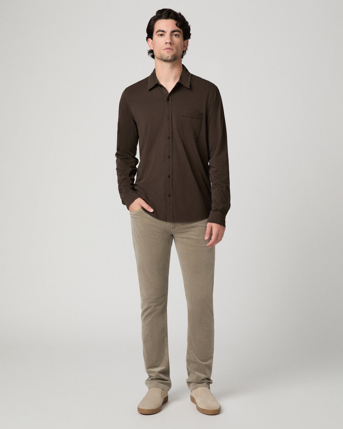 Man wearing a brown top and beige pants against a white background