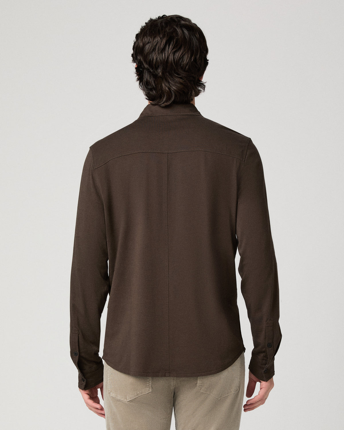 Man wearing a brown top and beige pants against a white background