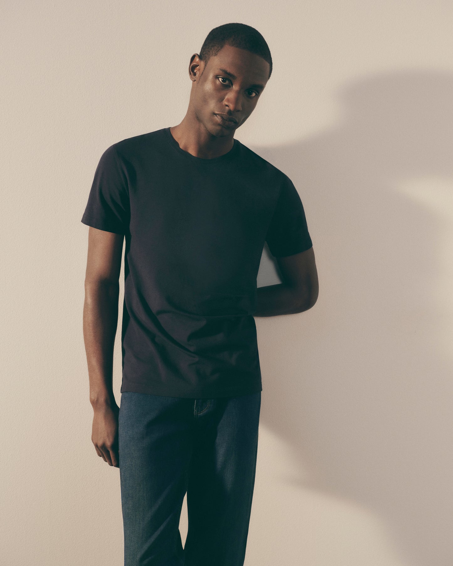 Man wearing a black t-shirt and pants against a plain background