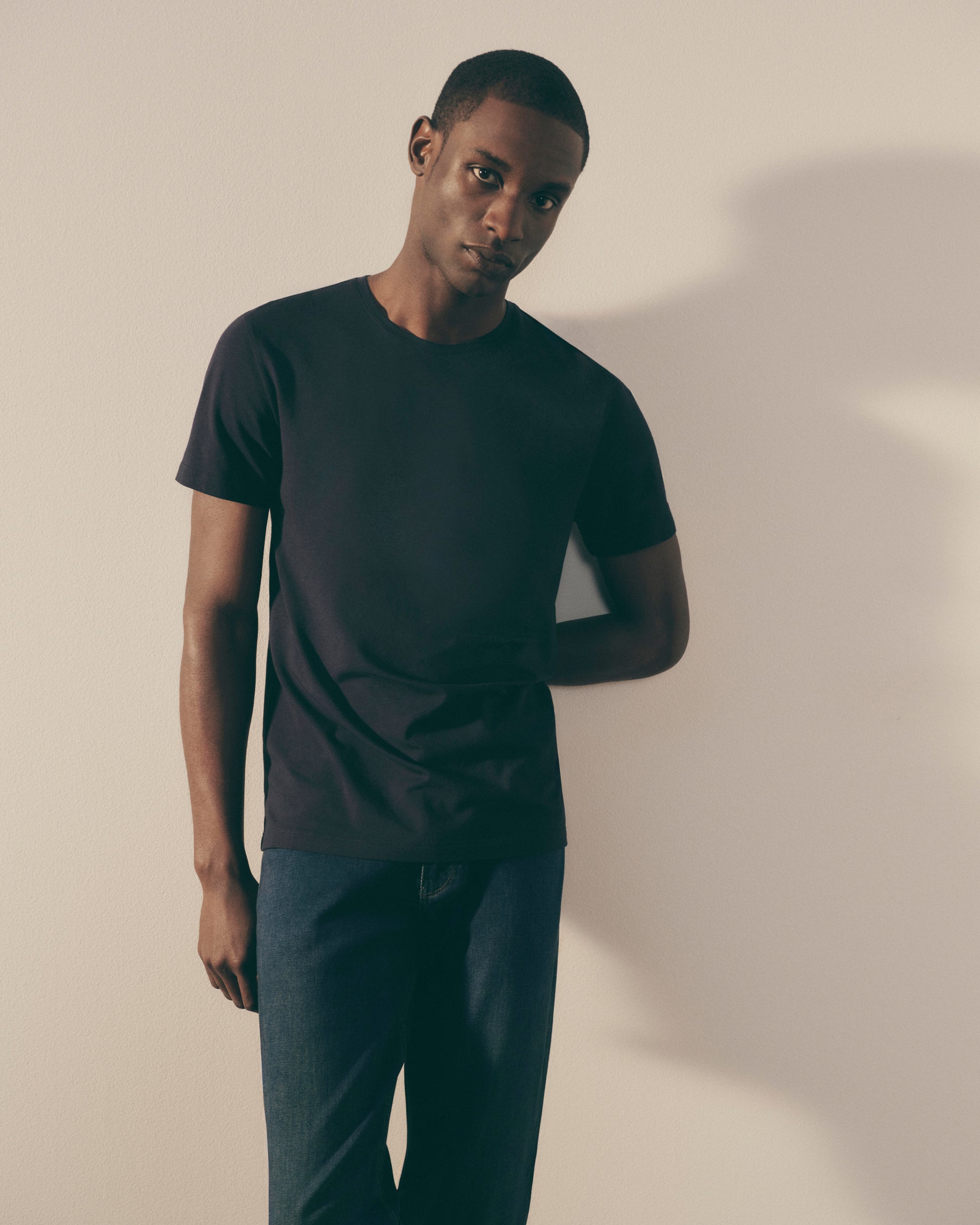 Man wearing a black t-shirt and pants against a plain background