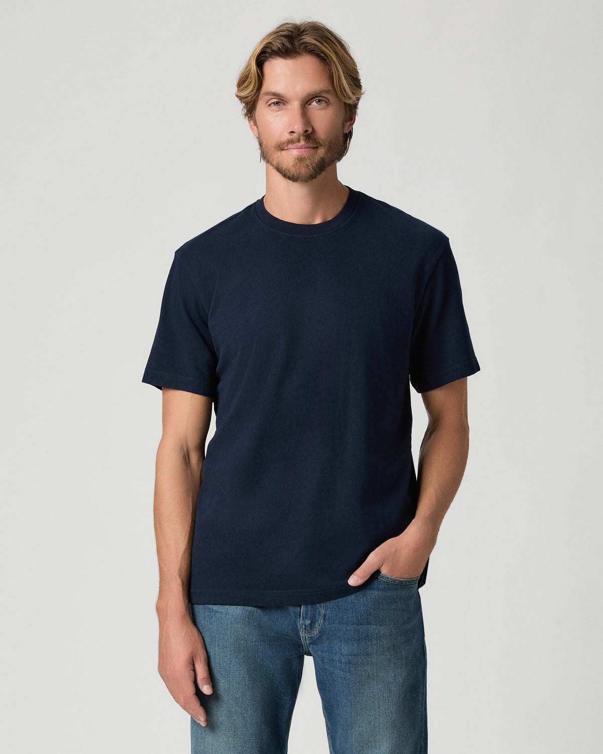Model standing with one hand in his pocket, wearing the Serano Boxy Tee in Hibernate, a navy short-sleeve tee, with medium-wash jeans