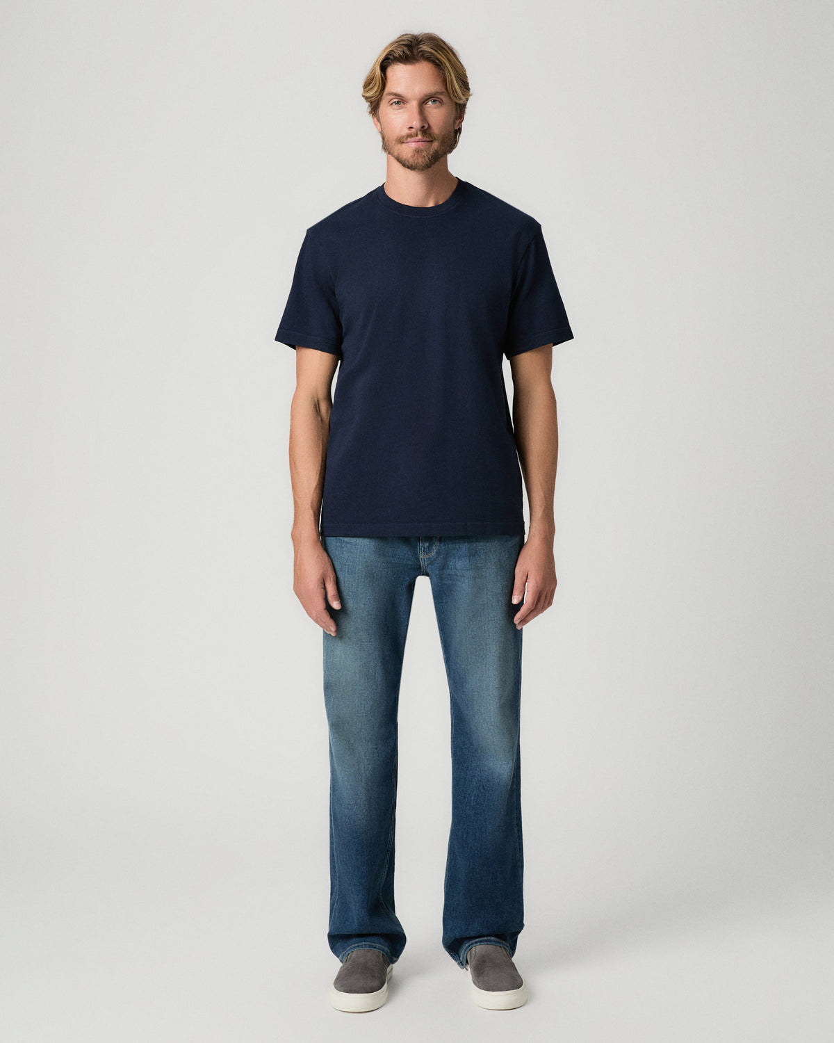 Full-length view of model standing with arms at his sides, wearing the Serano Boxy Tee in Hibernate with medium-wash jeans and grey shoes