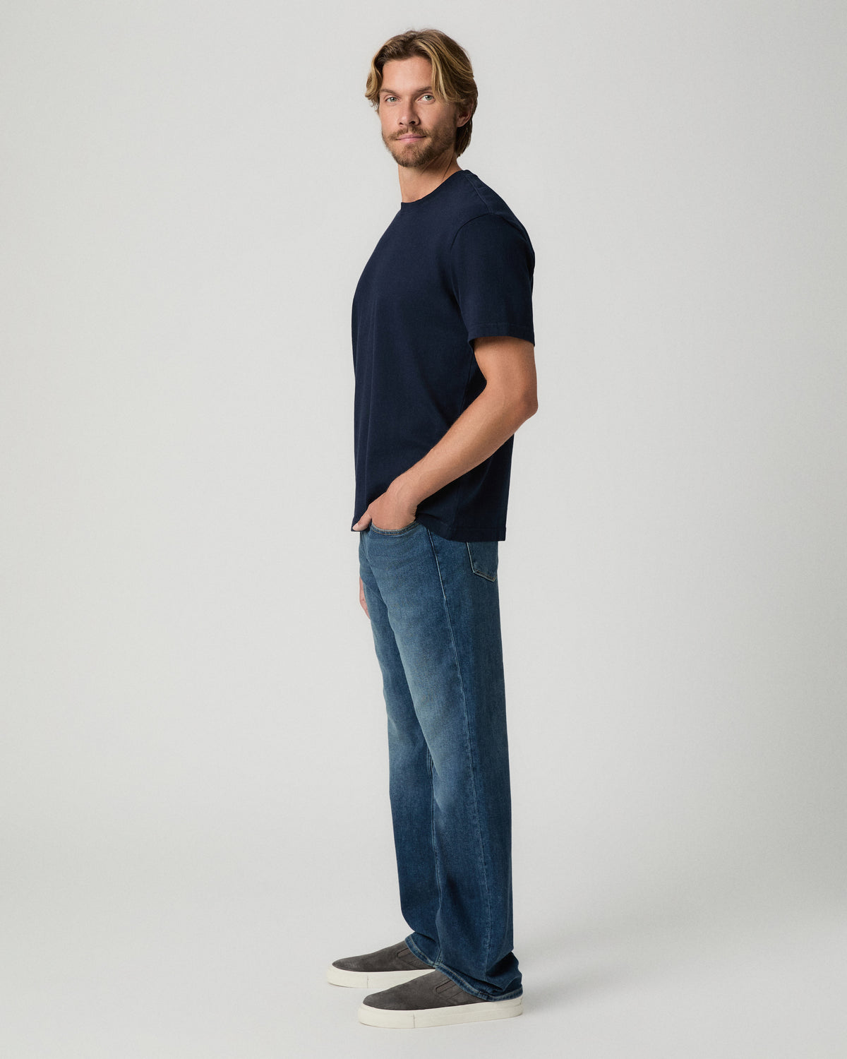 Side profile of model with one hand in his pocket, wearing the Serano Boxy Tee in Hibernate with medium-wash jeans and grey shoes