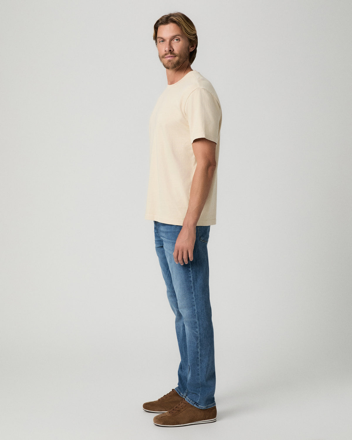 Side profile of model wearing the Serano Boxy Tee in Pale Antler with medium-wash jeans and brown suede shoes