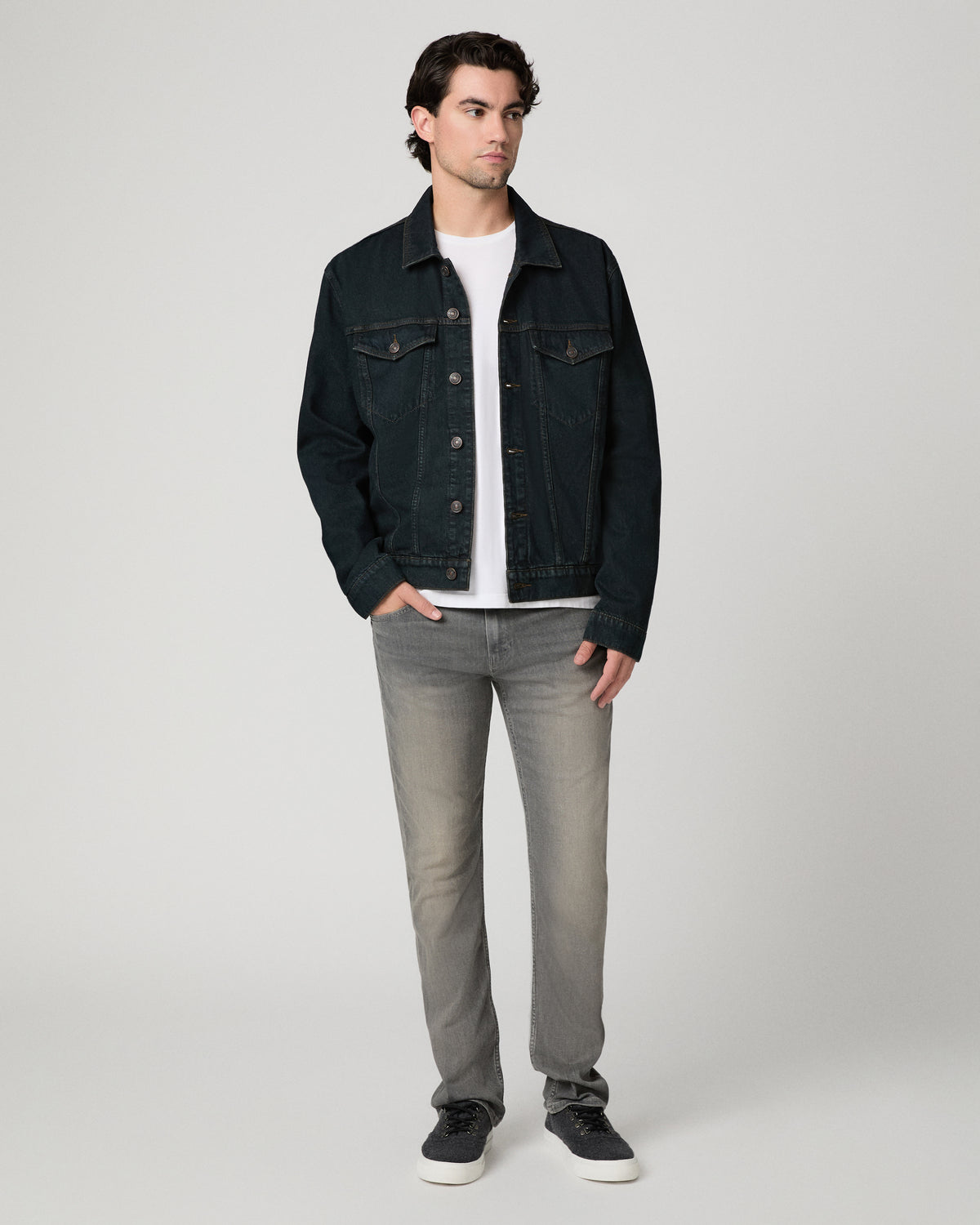 Man wearing white shirt with a dark blue jacket and grey jeans