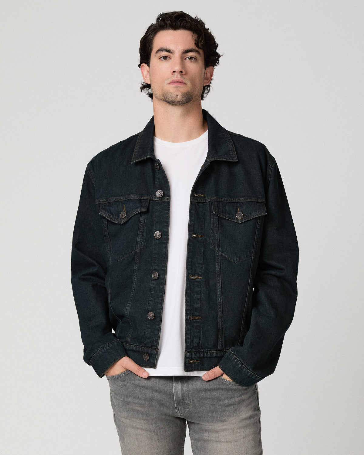 Man wearing white shirt with a dark blue jacket and grey jeans