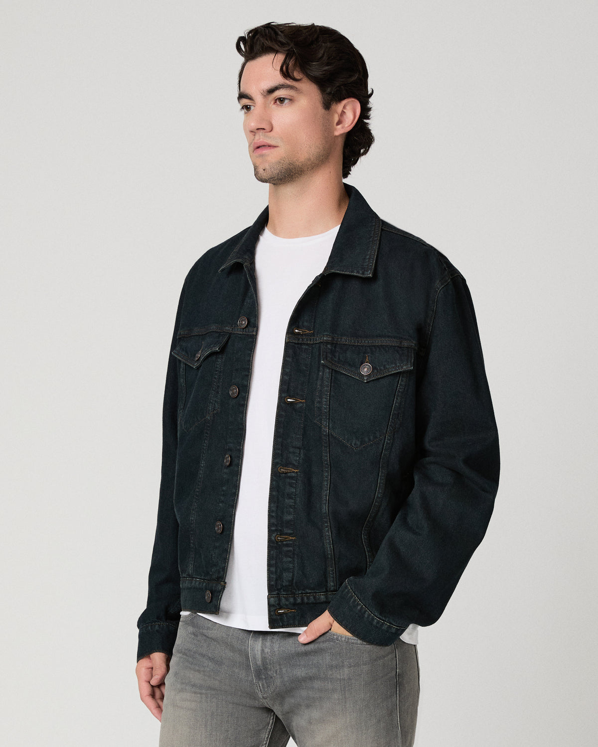 Man wearing white shirt with a dark blue jacket and grey jeans