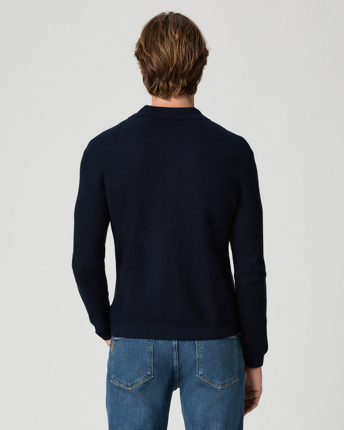 Back view of model wearing the Selwyn Sweater Polo in Deep Anchor with medium-wash jeans