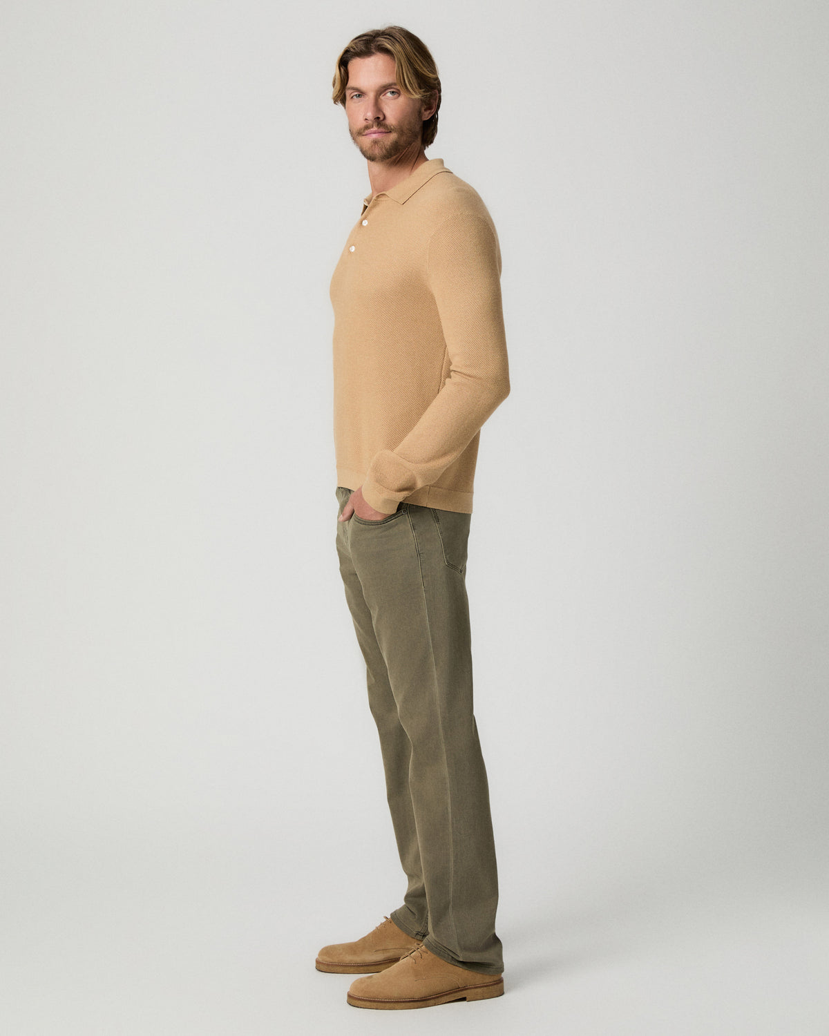 Side profile of model with one hand in his pocket, wearing the Selwyn Sweater Polo in Brown Russet with olive pants and tan suede boots