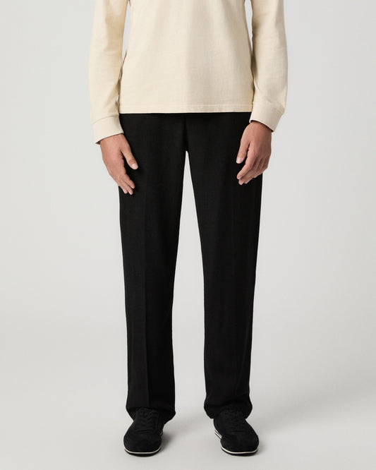 Front view from the waist down of the Tiano Pant in Black, a straight-leg pant, worn with a cream sweater and black shoes