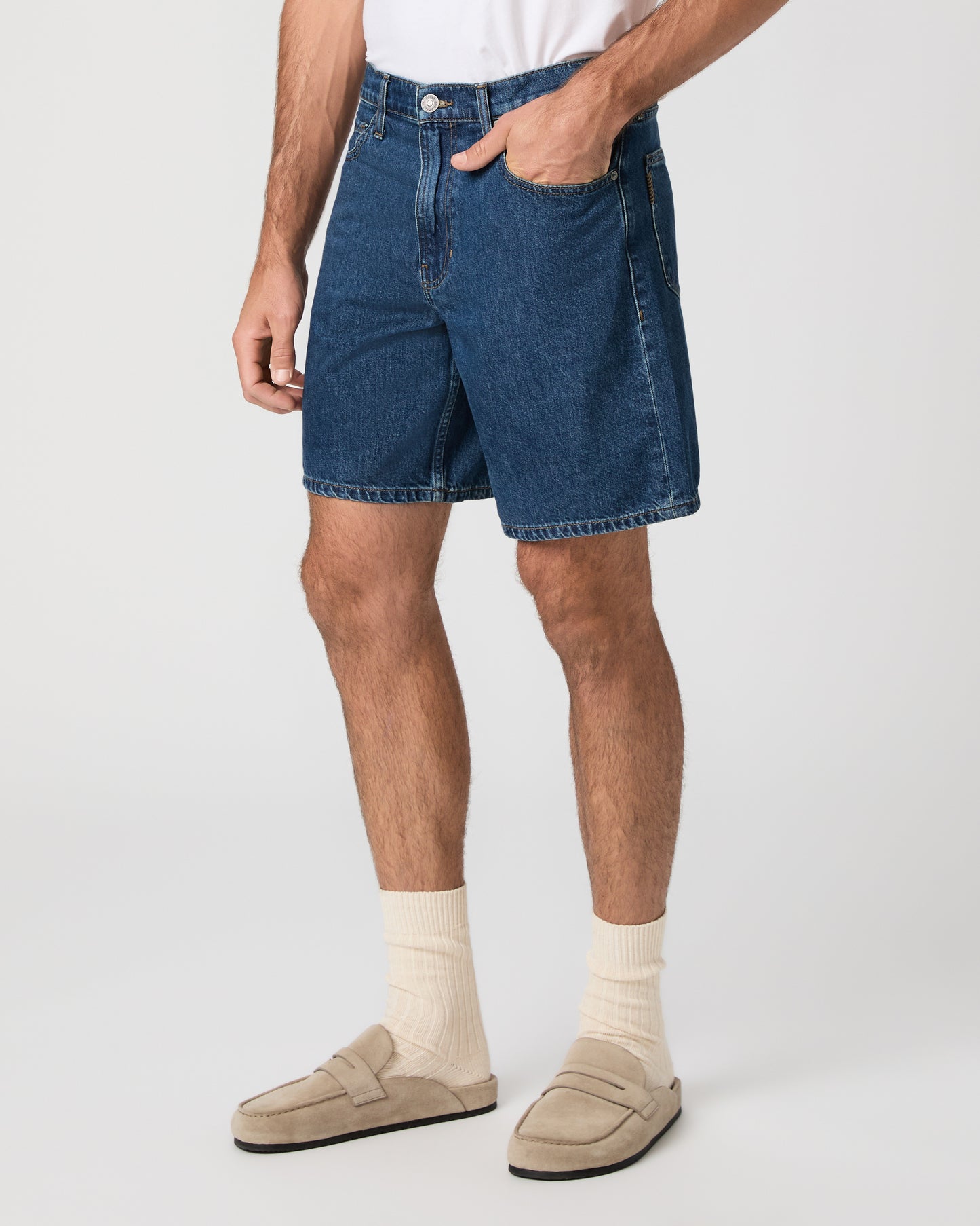 Man wearing a white t-shirt, blue shorts, and beige shoes on a white background