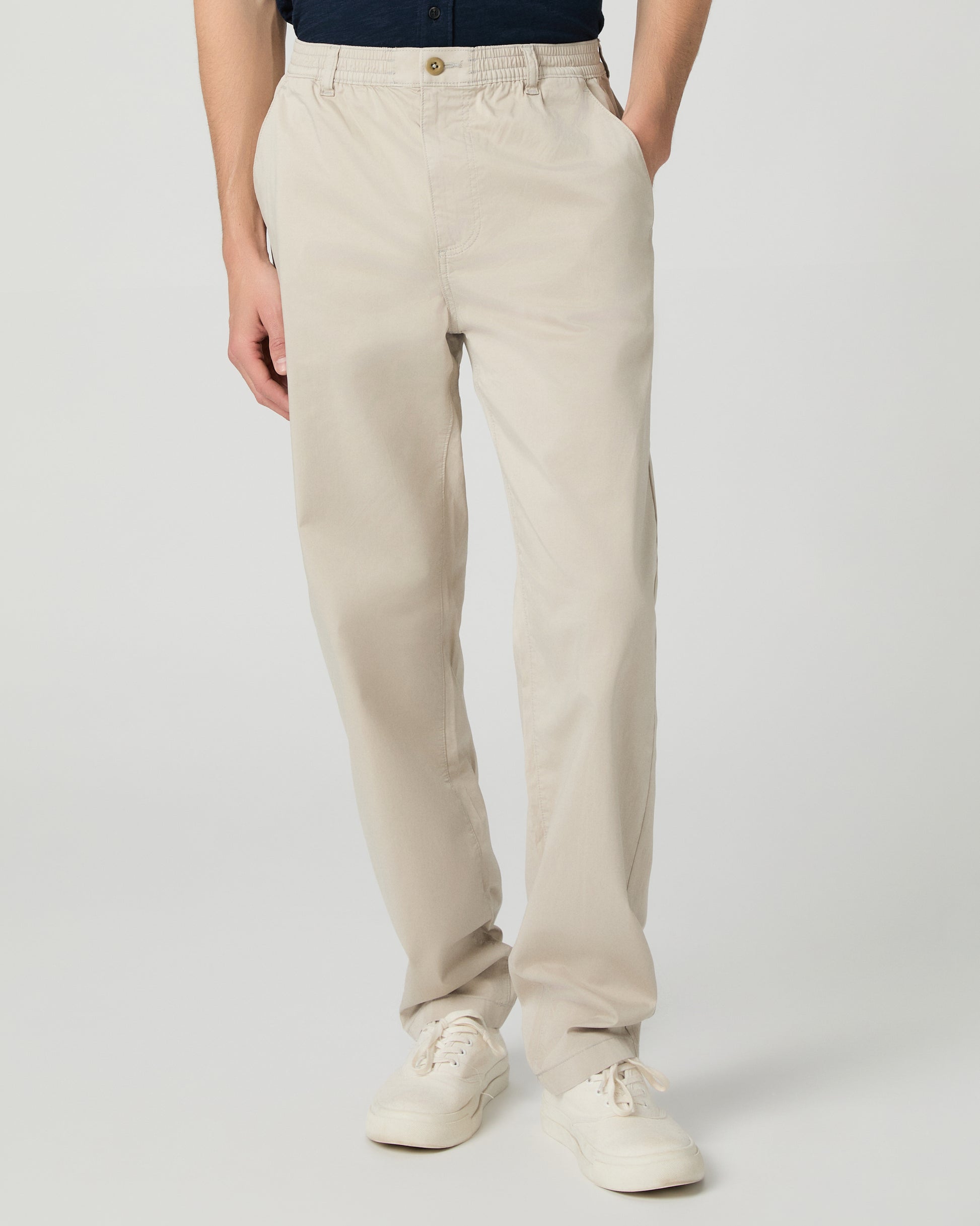 Man wearing a navy shirt and beige pants on a white background