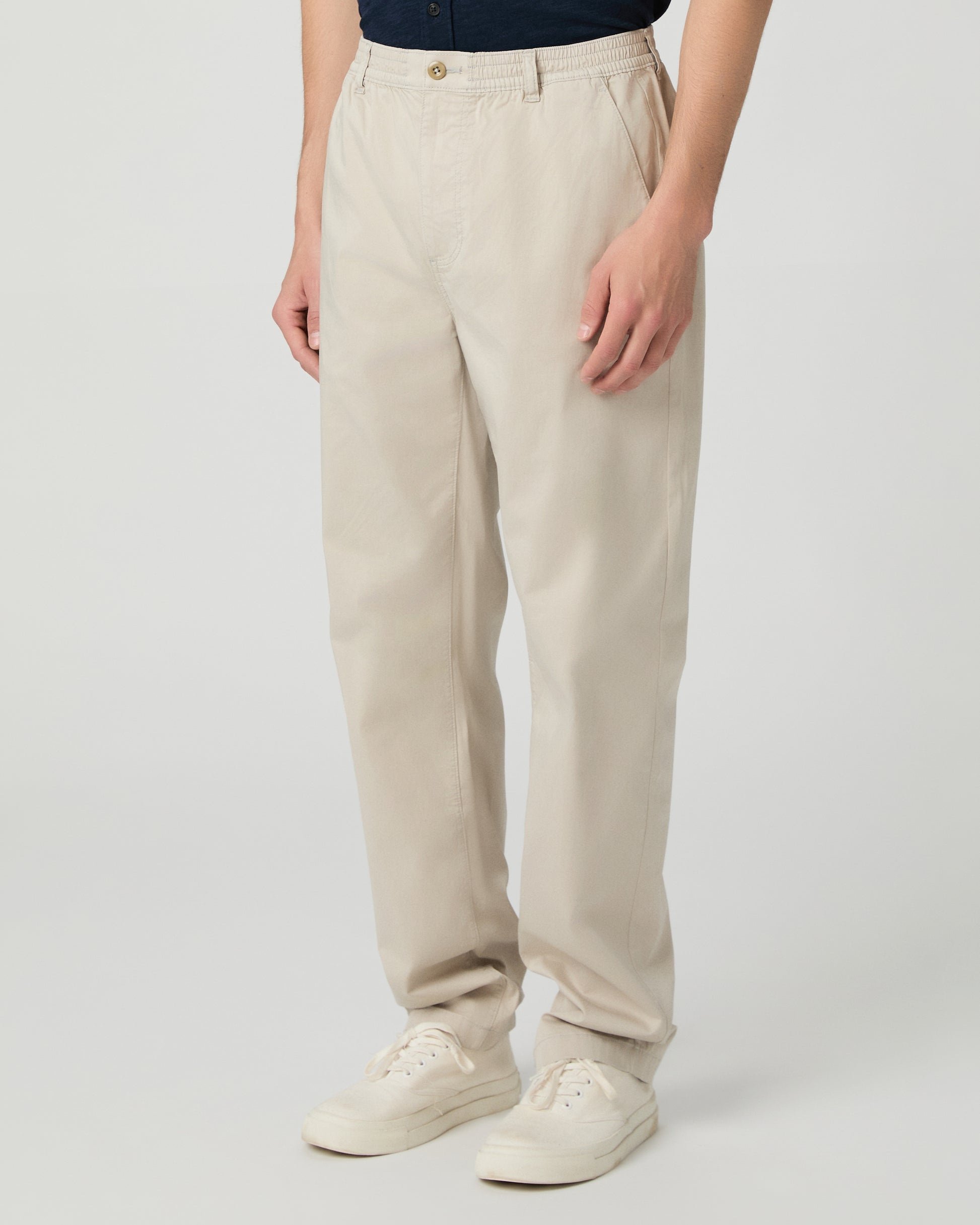 Man wearing a navy shirt and beige pants on a white background