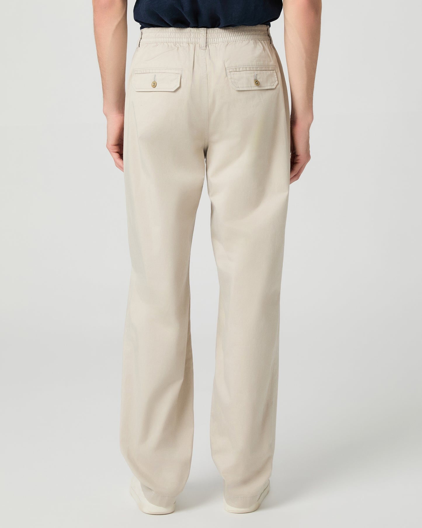 Man wearing a navy shirt and beige pants on a white background