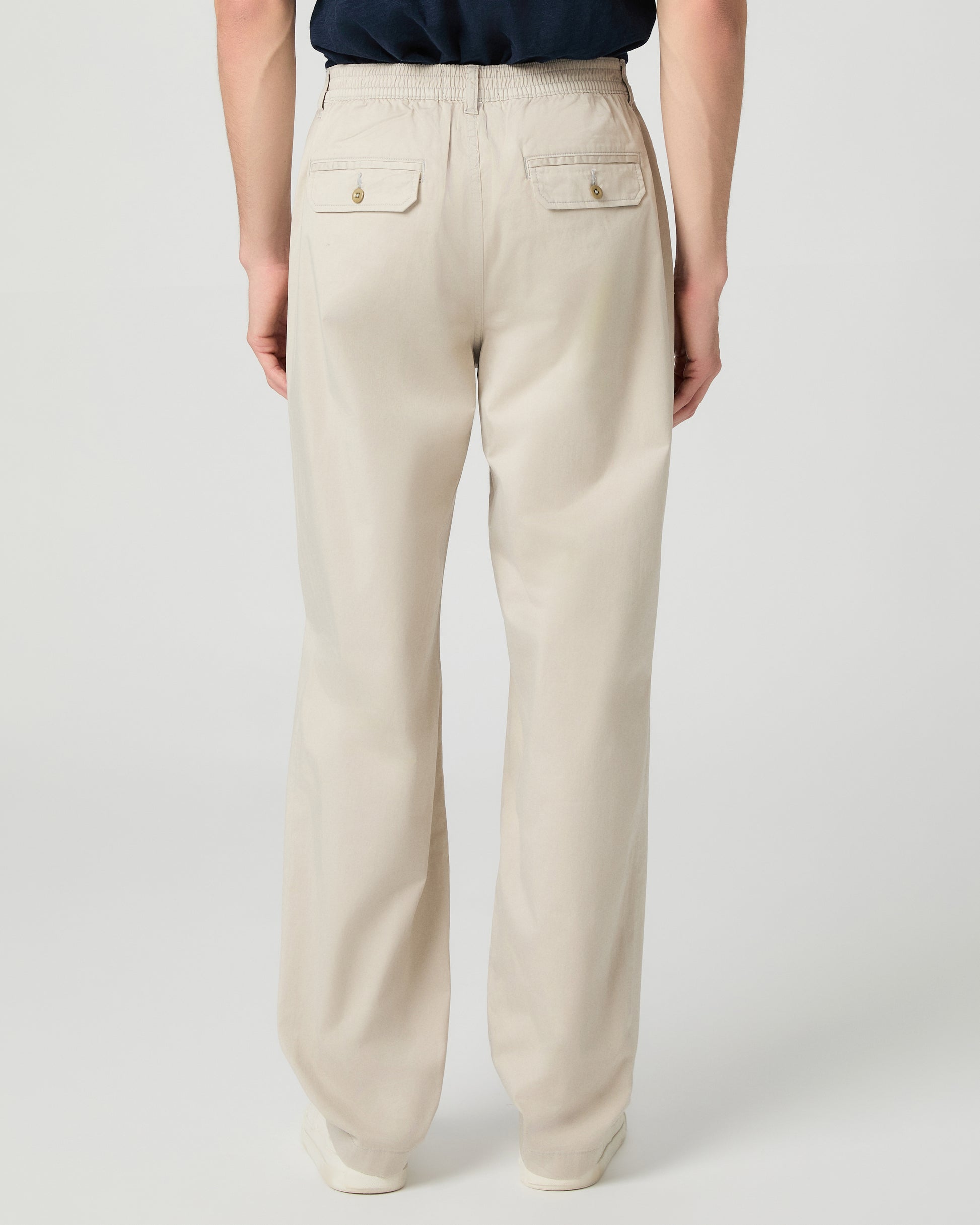 Man wearing a navy shirt and beige pants on a white background