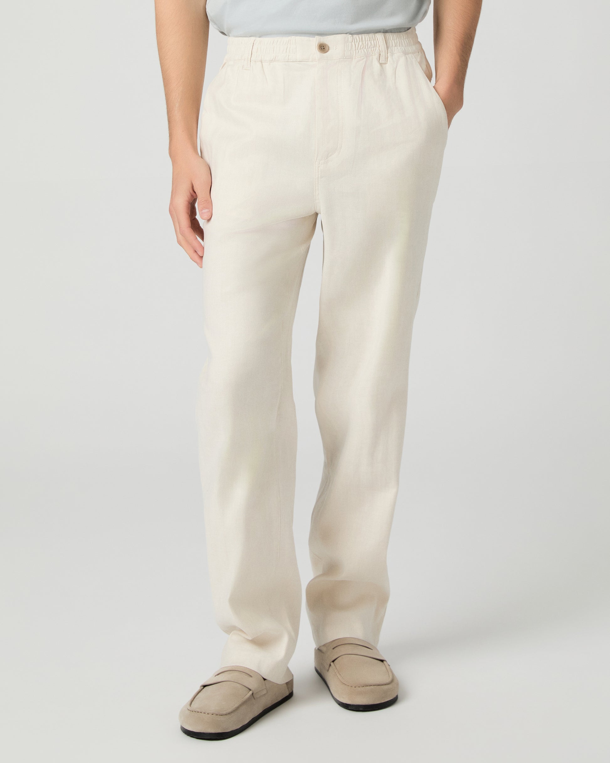 Man wearing a white tee, beige pants and slippers on a white background