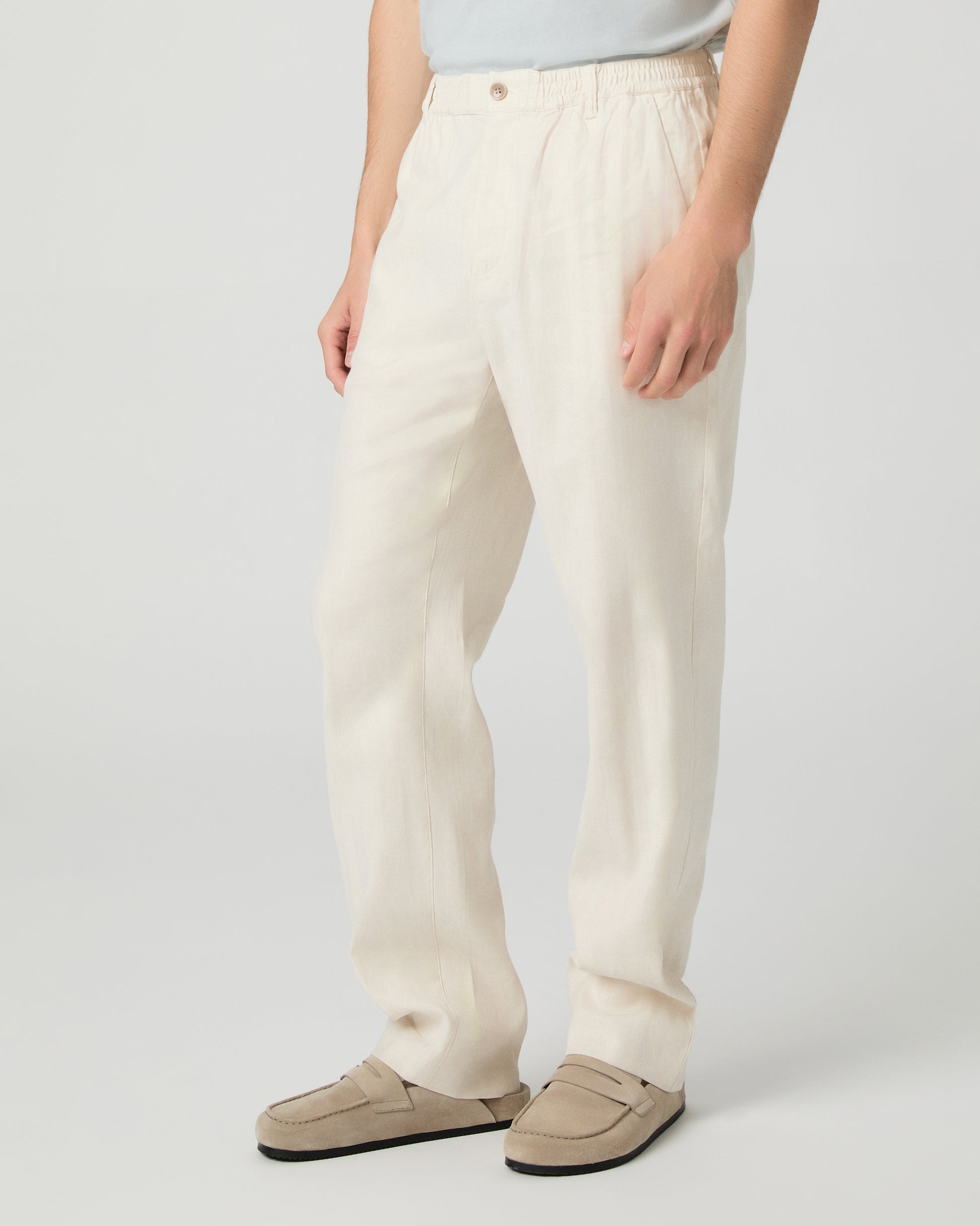 Man wearing a white tee, beige pants and slippers on a white background