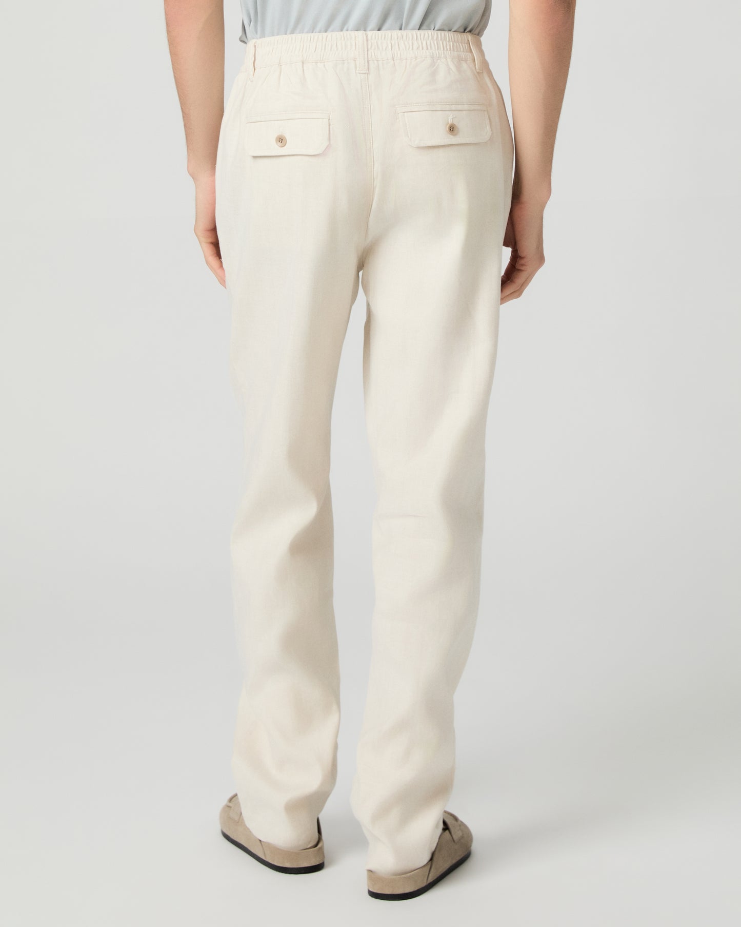 Man wearing a white tee, beige pants and slippers on a white background