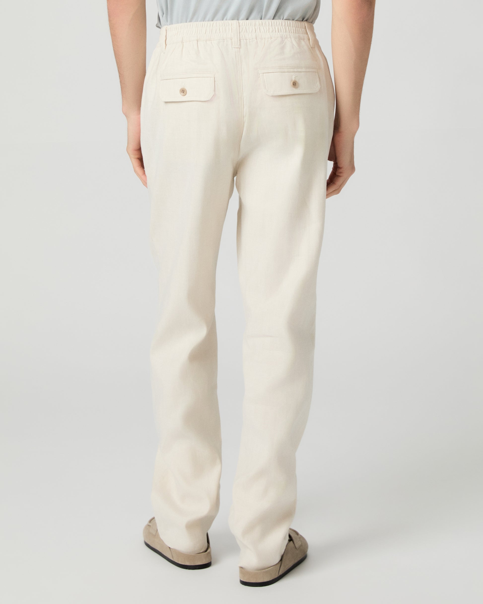 Man wearing a white tee, beige pants and slippers on a white background