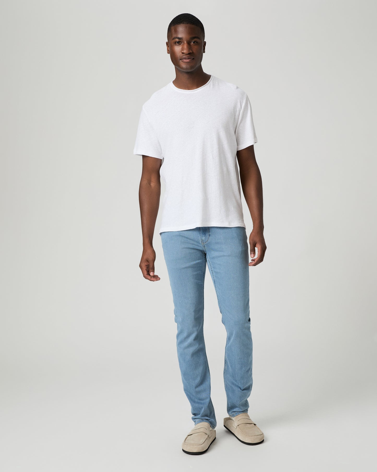 Man wearing a plain white t-shirt and light blue jeans against a white background