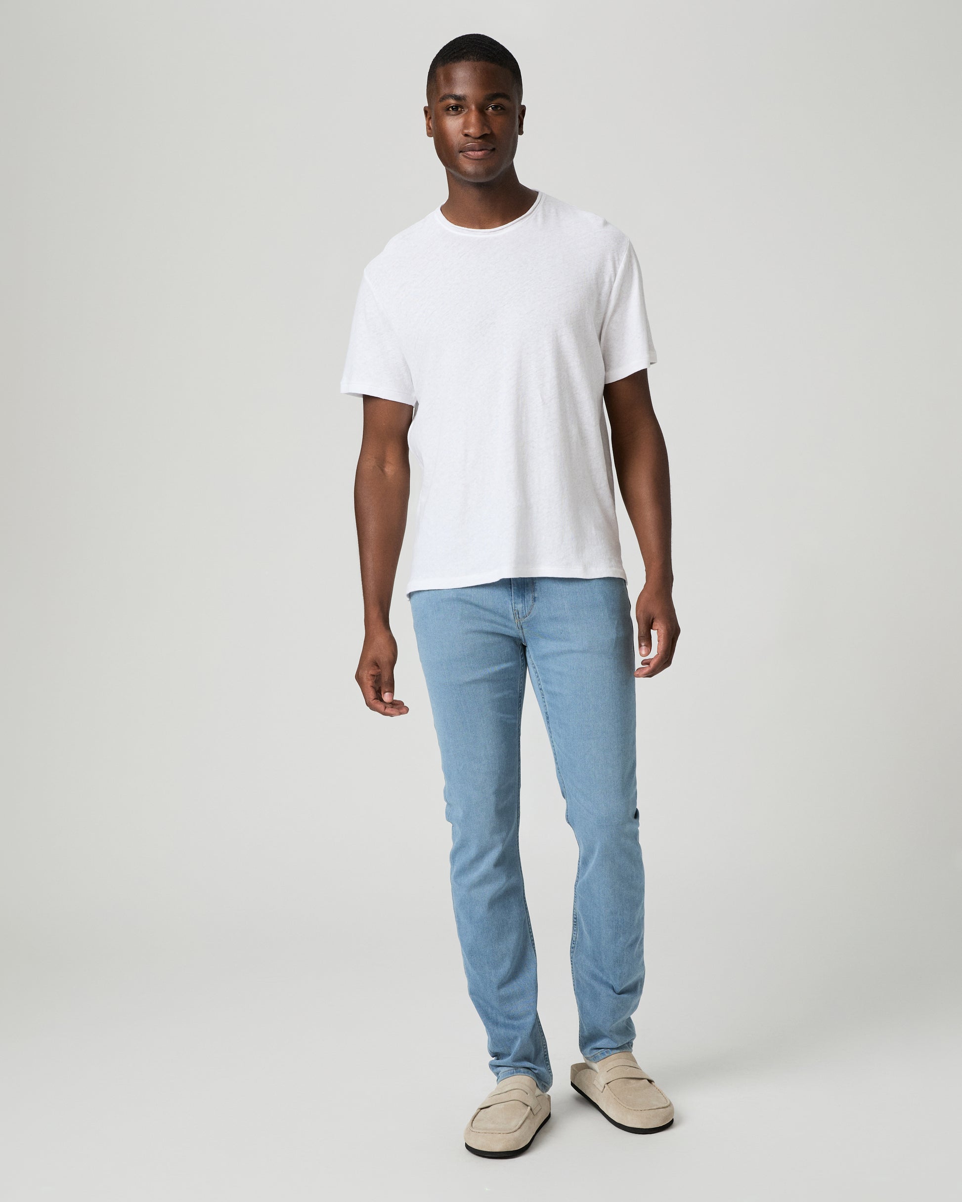 Man wearing a plain white t-shirt and light blue jeans against a white background