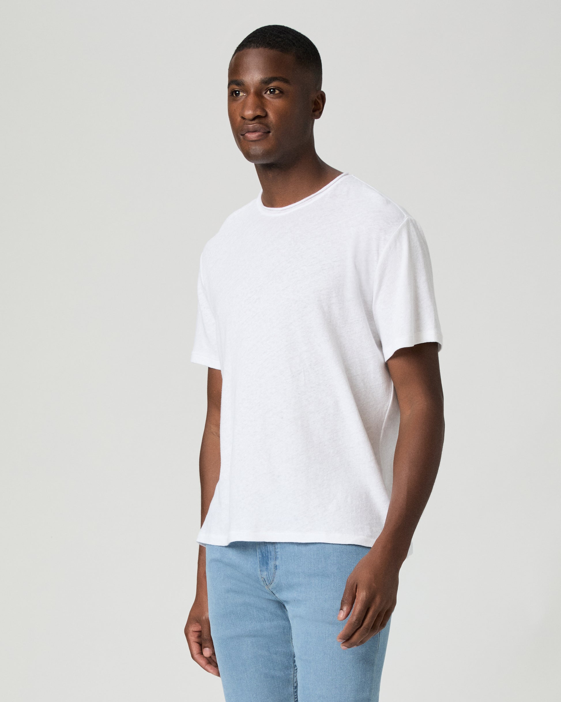 Man wearing a plain white t-shirt and light blue jeans against a white background
